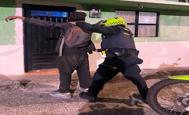 una casa, un ciudadano y un uniformado realizando registro a persona