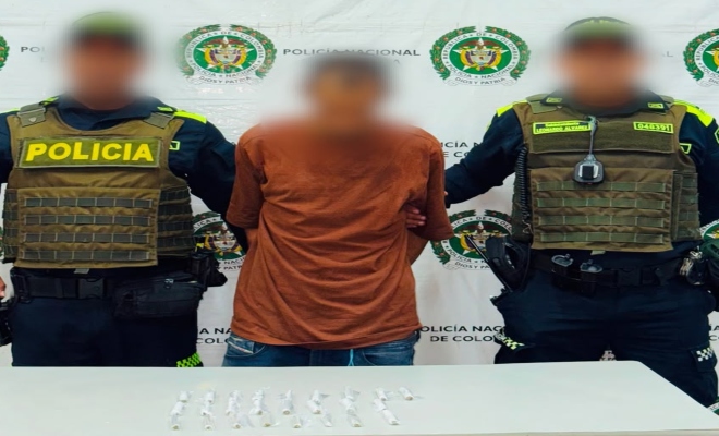 Dos funcionarios policiales con un ciudadano capturado frente a pend&oacute;n institucional 