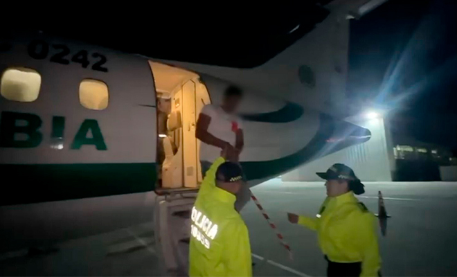 Dos funcionarios de Policía ayudan a descender de un avión a un capturado