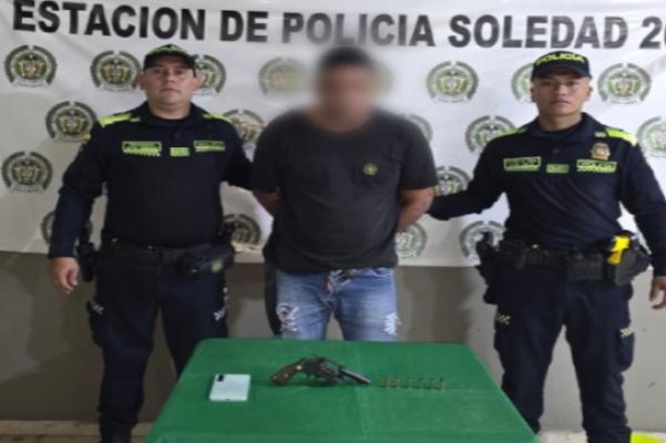 Dos policías, un capturado y arma de fuego encima de la mesa