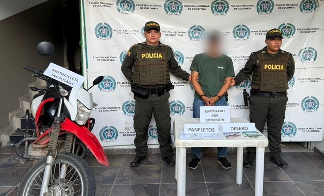 Dos polic&iacute;as con un capturado y una motocicleta