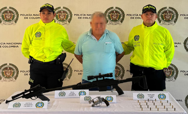 Se observa dos uniformados de la SIJIN con una persona capturada tres armas de fuego y 22 cartuchos sobre una mesa