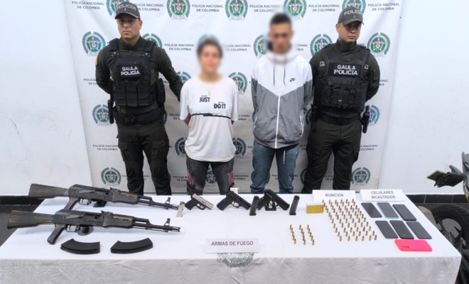 Dos policías del GAULA custodian a dos capturados por extorsión