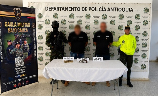 Un Polic&iacute;a y un soldado del Ej&eacute;rcito custodian capturados y armamento
