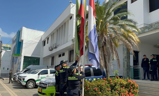 Tres policías izando la bandera 
