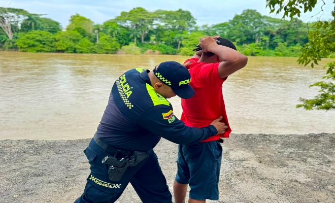 un uniformado de la Policía nacional realizando registro a un ciudadano en vía publica 