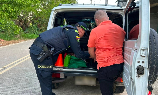 Funcionario policial realizando registro a vehículo y al lado un ciudadano 