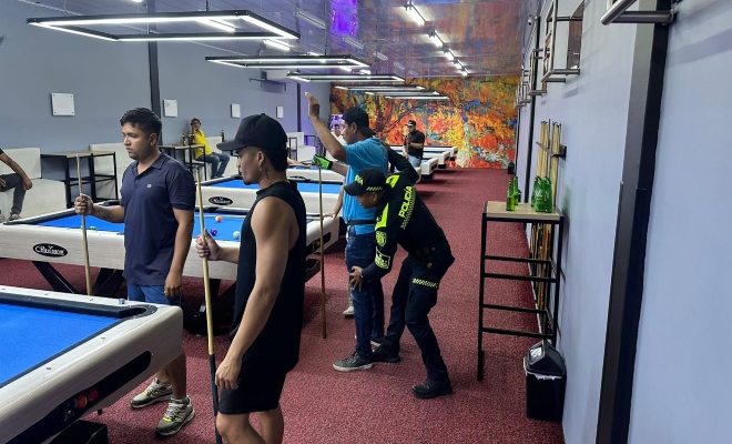 Un policía realizando registro a ciudadanos dentro de un Billar