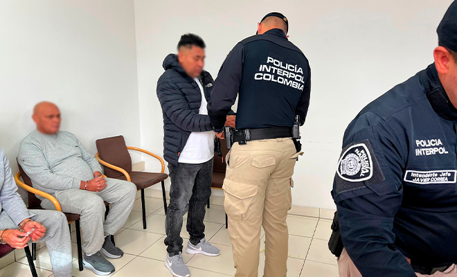 Funcionario de INTERPOL coloca las esposas a capturado, para ser extraditado.