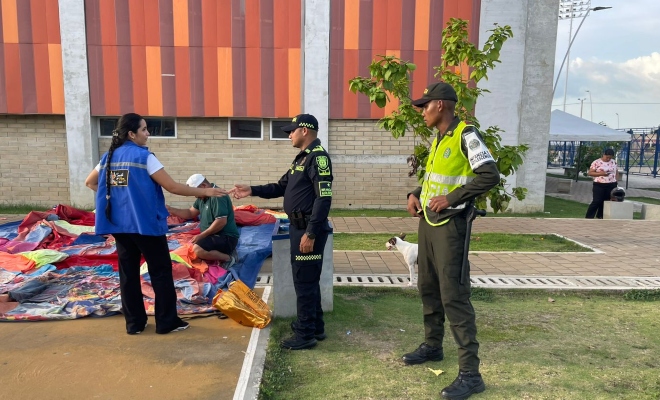 Dos funcionarios policiales brindando recomendaciones y saludando de mano a una ciudadana 
