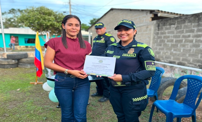 funcionaria policial hace entrega a ciudadana de diploma  programa Espacios Pedagógicos para la Convivencia y la Seguridad Ciudadana