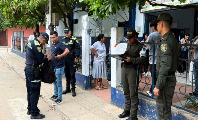 cuatro uniformados  realizando registro a persona en una institución educativa 