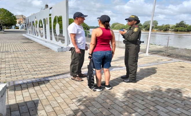 Un policía realizando charla de prevención a dos ciudadanos 