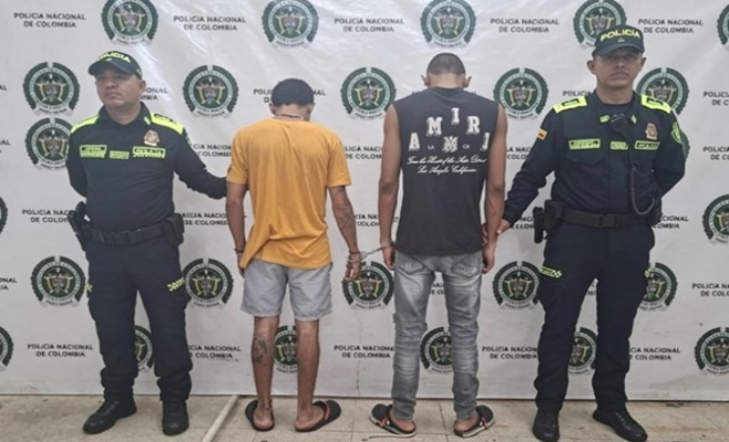dos polic&iacute;as custodian dos sujetos que est&aacute;n de espalda capturados por orden judicial 