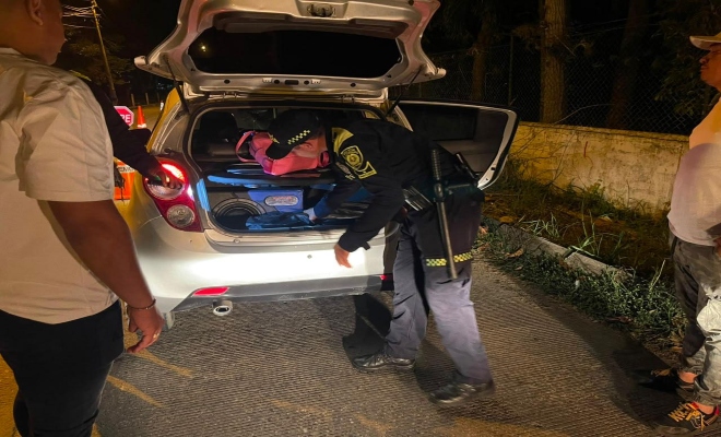 un uniformado de la policía nacional  realizando un registro a un vehículo 
