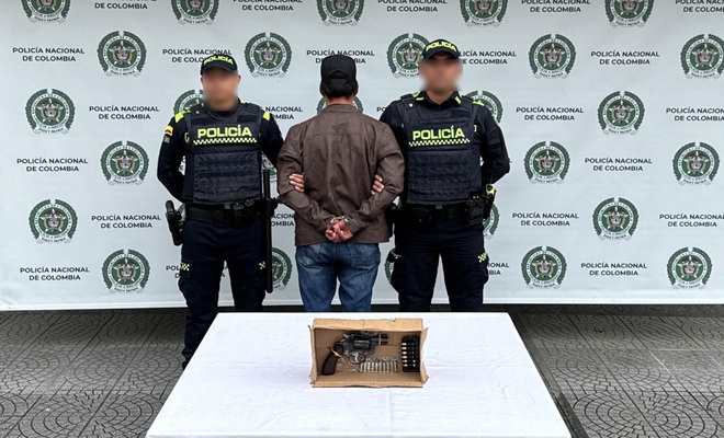 dos polic&iacute;as, un capturado, una mesa y un arma de fuego incautada 