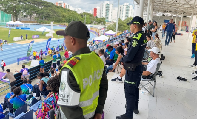 Dos funcionarios policiales prestando servicio de acompañamiento en espacio deportivo rodeado de la ciudadanía 