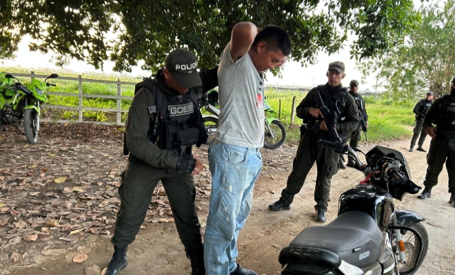 Cinco funcionarios policiales en actividad de control, uno realizando registro a persona a un ciudadano