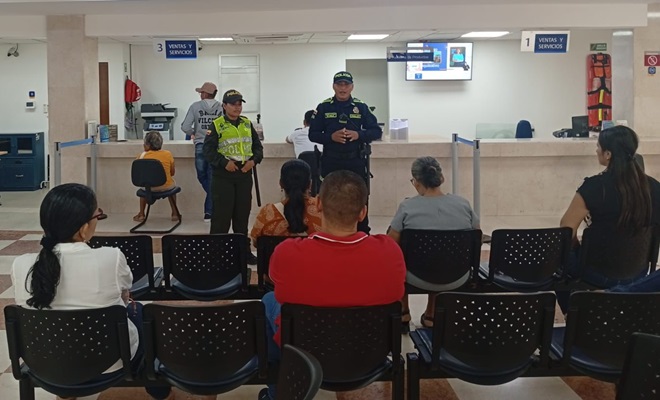 Dos funcionarios policiales realizando una charla a usuarios de un banco