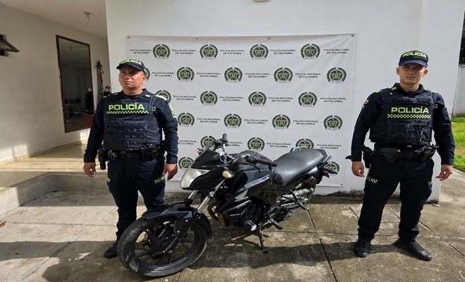 una motocicleta recuperada y dos policias a los lados 