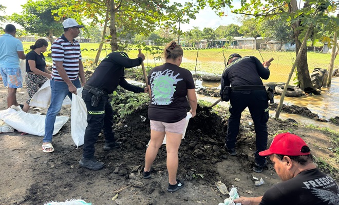 Policía y comunidad llenando costales con arena