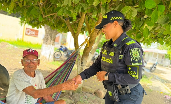 Funcionaria policial en compañía de un adulto mayor saludándolo de mano sonriendo