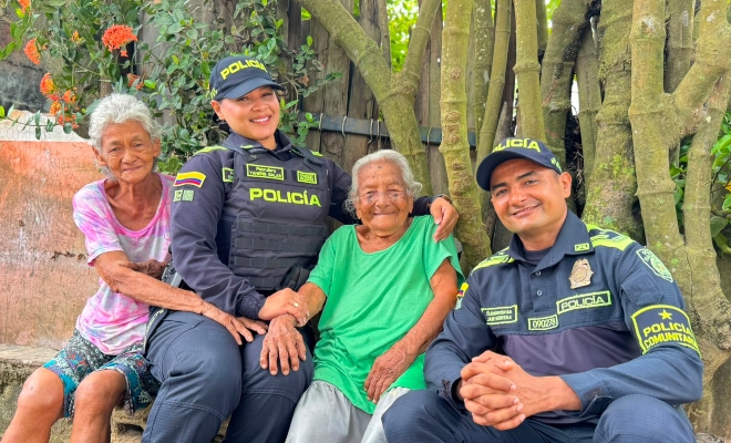 Dos funcionarios policiales junto a dos ciudadanas mayores sentados y sonriendo a la cámara 