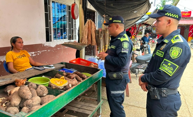 Dos funcionarios del grupo de policía comunitaria brindando recomendaciones de seguridad a una ciudadana en sector comercio 