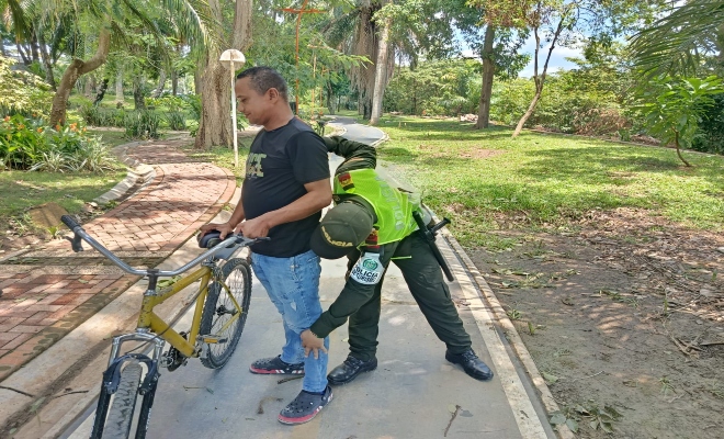 un uniformado de la policía nacional realiza un registro a personas en el parque principal de la ciudad de Montería