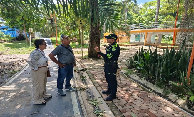 un uniformado de la policía nacional con dos personas brindándoles recomendaciones 