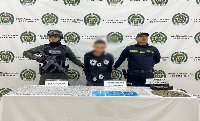 Dos uniformados con una persona capturada por el delito de tráfico de estupefacientes, elementos que se encuentran encima de una mesa