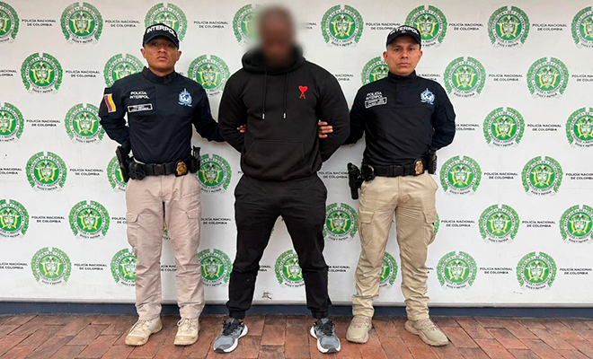 Dos funcionarios de Interpol custodian a una persona en calidad de retenido