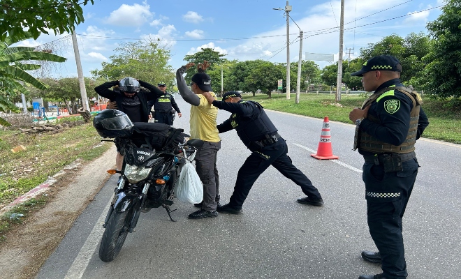 Dos policias registrando a dos ciudadanos y dos policias prestando seguridad 