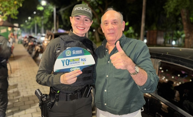 Ciudadano junto a una funcionaria policial del GAULA sonriendo mirando a la cámara 