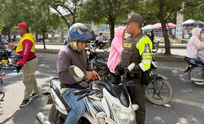 un uniformado adscrito a la seccional de transito y transporte realizando charlas preventivas a ciudadanos en vía principal de la ciudad de montería