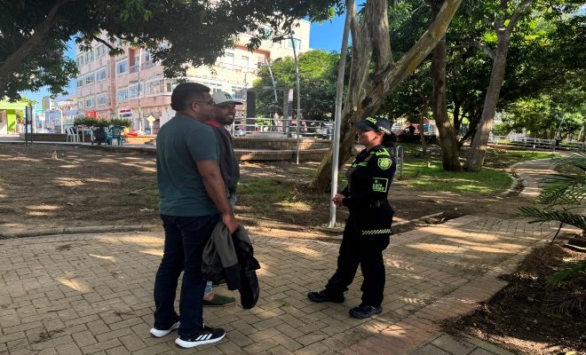 una funcionaria de la policía nacional brinda recomendaciones a dos ciudadanos en la ciudad de montería