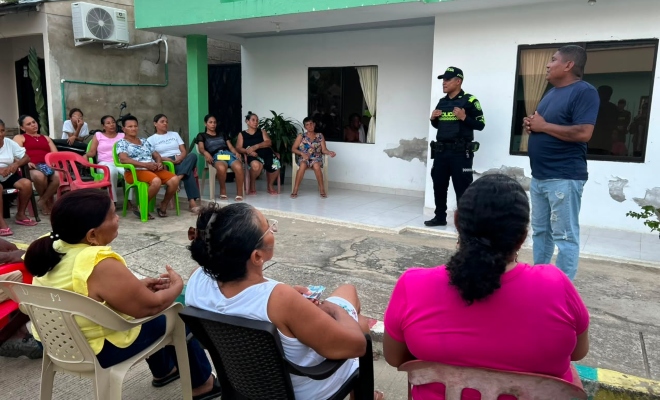 Funcionario policial frente a un grupo de personas brindando recomendaciones en encuentro comunitario