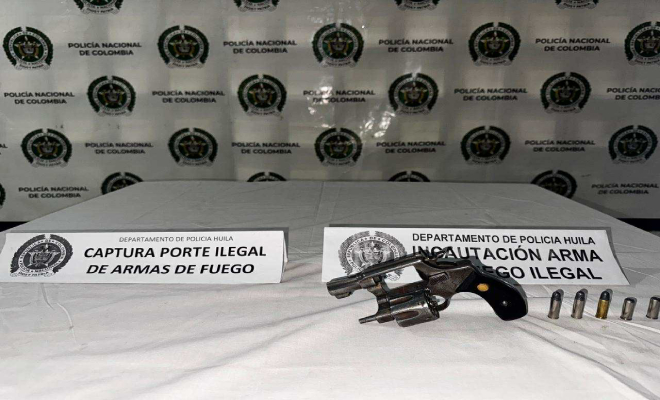 Arma de fuego en una mesa con cartuchos para la misma al lado