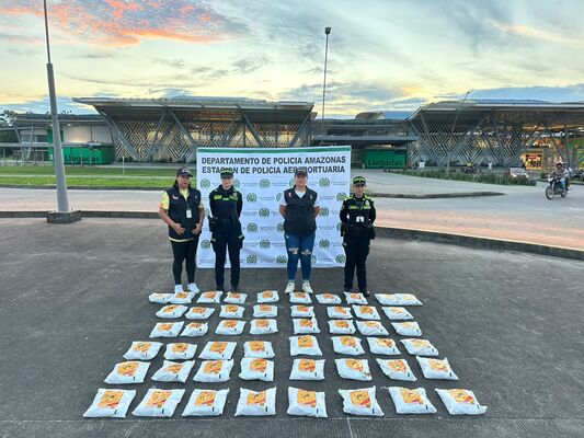 Cuatro personas, entre ellas 2 Policías, posando frente a las instalaciones de la estación policial en Amazonas, con una gran cantidad de paquetes dispuestos en el suelo, correspondientes a sustancias ilícitas que fueron incautadas durante una operación de control y seguridad