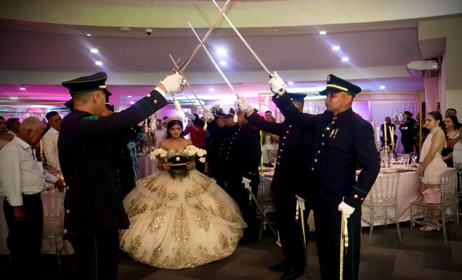 Ingreso de la quinceañera bajo arco de honor.