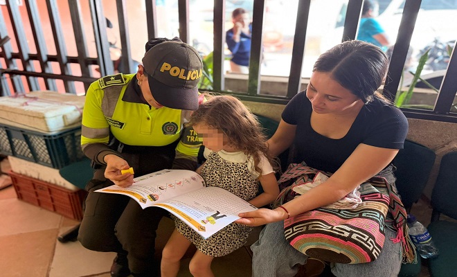 Uniformada de la Seccional de Tránsito y Transporte de la Policía Nacional brindando campaña de sensibilización sobre las señales de tránsito a una niña en compañía de su madre 