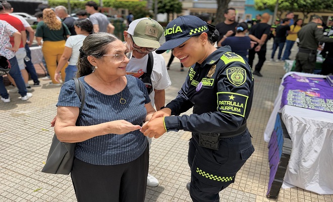 una uniformada del grupo de Patrulla Púrpura brindando campaña de sensibilización y prevención a una ciudadana  