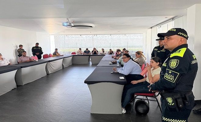 Cuatro funcionarios de la Policía Nacional en compañía de catorce ciudadanos integrantes del gremio hotelero sentados en mesa redonda siendo participes de una capacitación 