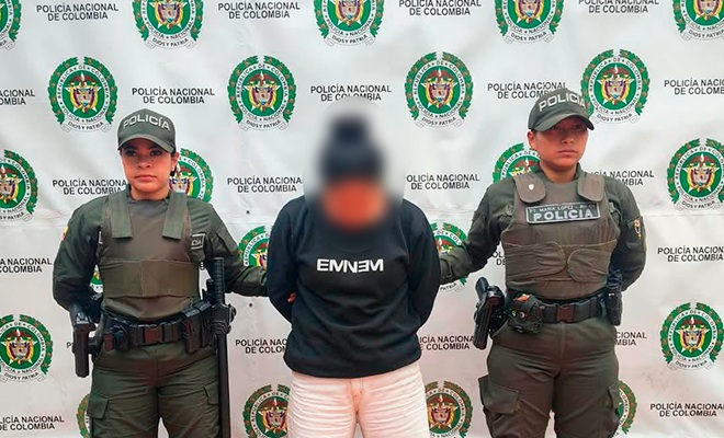 Mujer capturada y esposada con dos policías en cada lado respectivamente 