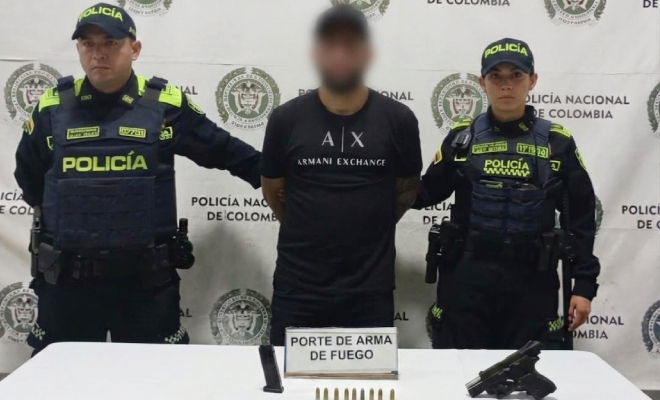 Capturado y dos uniformados y un arma de fuego sobre la mesa