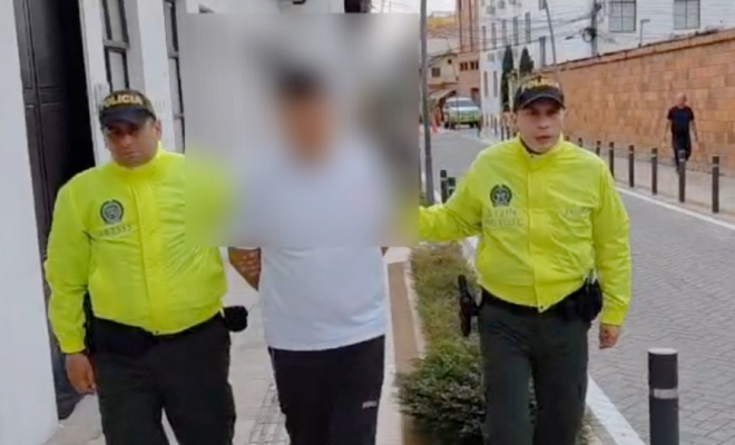 Hombre capturado viste de camiseta blanca en medio de dos policías