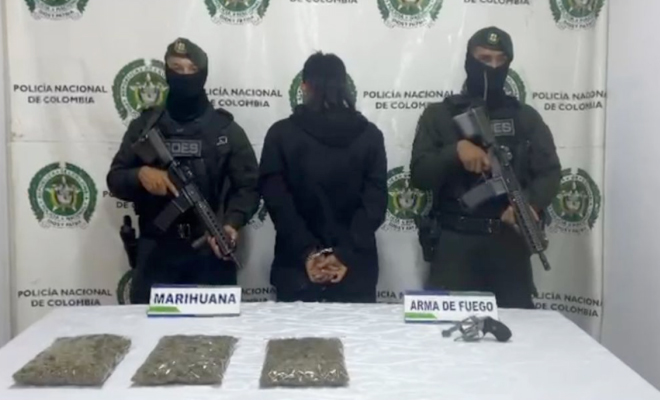 Hombre capturado en medio de dos policías, en frente elementos incautados