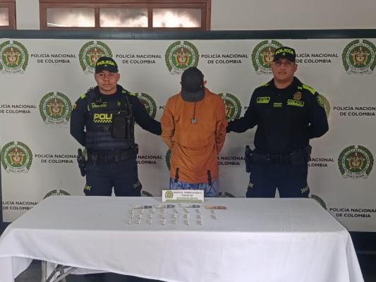 Hombre capturado con camiseta color naranja en medio de dos Policías