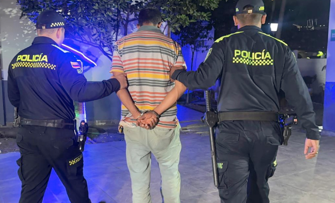 Hombre capturado con las manos esposadas en medio de dos policías