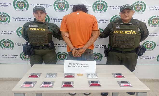 Persona esposada junto a personal de la Policía Nacional y varios dispositivos reflectivos solares sobre una mesa